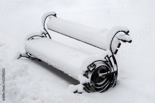 The bench in the park after a heavy snowfall is covered with a thick layer of snow