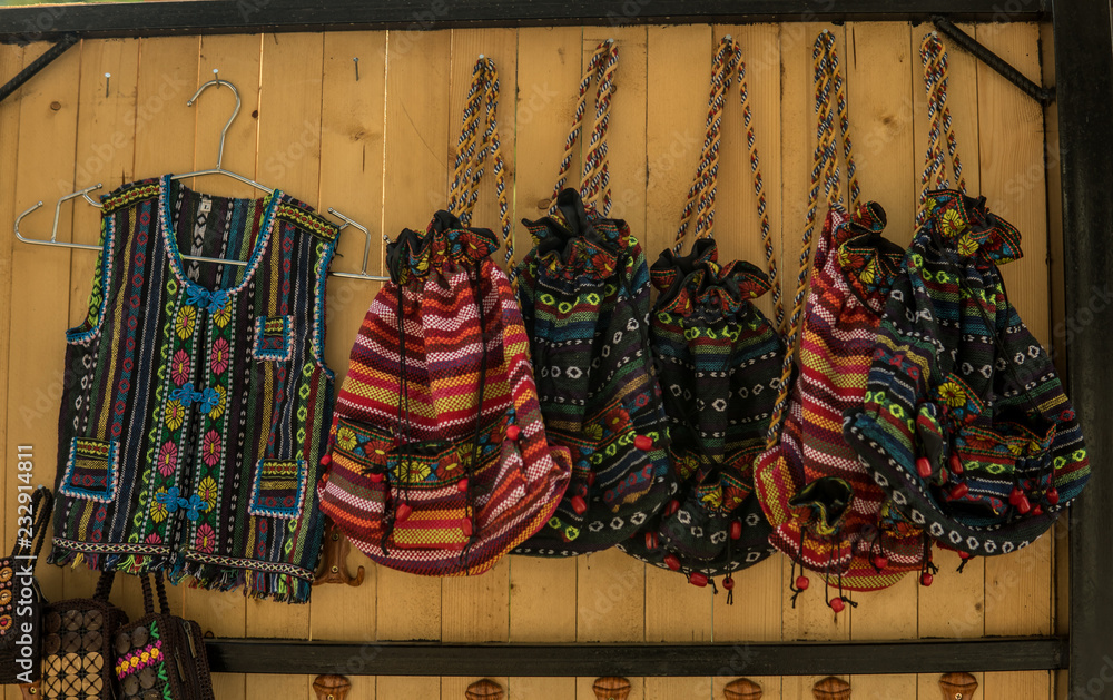 Woven shirts and Backpacks hanged up with wood bacground. Old vintage tribal or ethnic style.