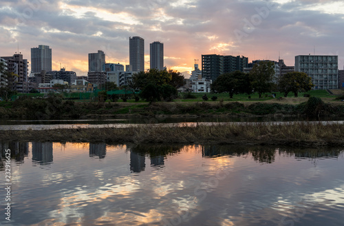 the sun sets in the buildings across the Tama River Kawasaki Kanagawa Japan