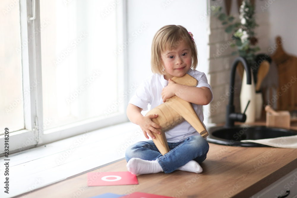 Toddler with Down syndrome plays with wooden horse Toddler with Down syndrome plays with wooden horse