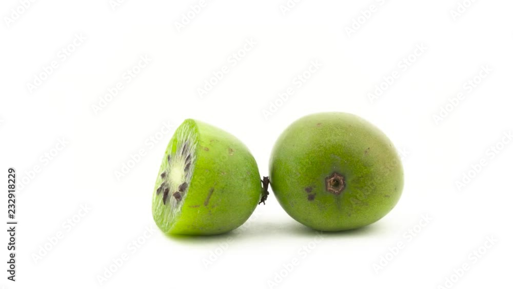One whole and one half of baby kiwi fruit. Rotating on the turntable. Isolated on the white background. Close-up. Macro. One whole and one half of baby kiwi fruit. Rotating on the turntable. Isolated on the white background. Close-up. Macro.