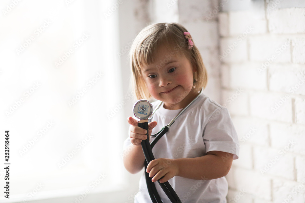 Fototapeta premium Toddler with Down syndrome plays with stethoscope