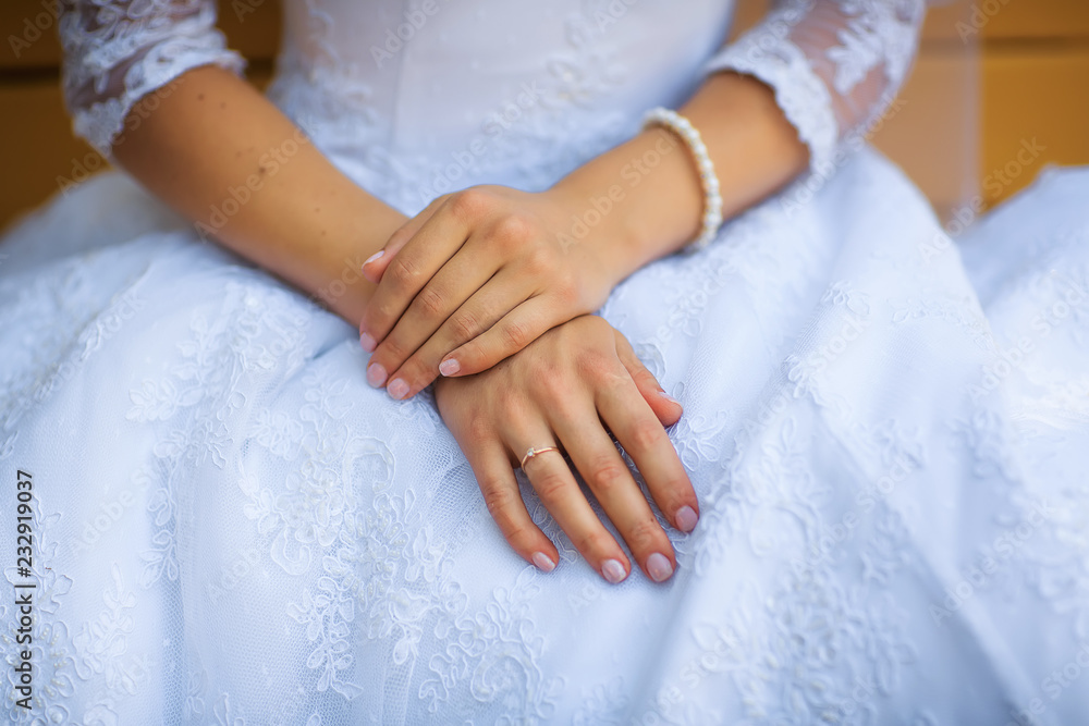 The palm of the bride with a ring and a bracelet on the background of a white dress The palm of the bride with a ring and a bracelet on the background of a white dress