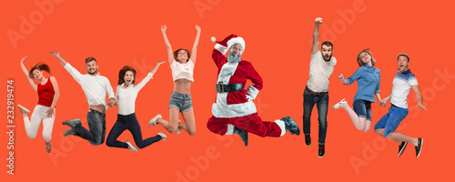 Freedom in moving. Mid-air shot of pretty happy young man and women jumping and gesturing against studio background. Runnin girl and Santa. Christmas and holiday concept