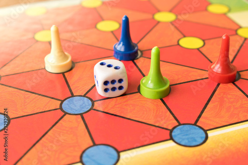 Multi-colored game chips with dice on the playing board. Board game