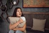 Scared teen at home embracing pillow  in living room at home