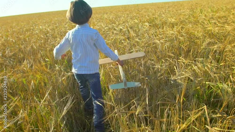 Happy little boy child running with toy airplane in wheat field at sunset. Kid playing with airplane in summer nature outdoors. Little pilot dreaming of flight, vacation with happy family, big dream. Happy little boy child running with toy airplane in wheat field at sunset. Kid playing with airplane in summer nature outdoors. Little pilot dreaming of flight, vacation with happy family, big dream.