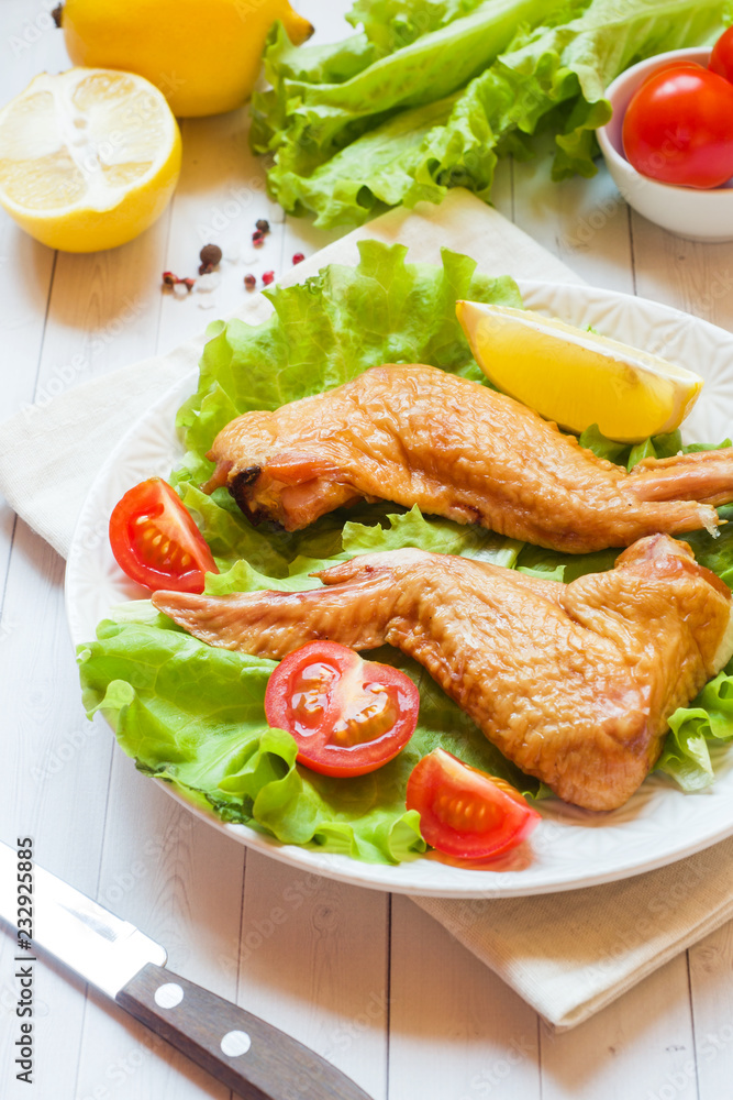 Smoked chicken wings with fresh lettuce tomato and lemon Smoked chicken wings with fresh lettuce tomato and lemon