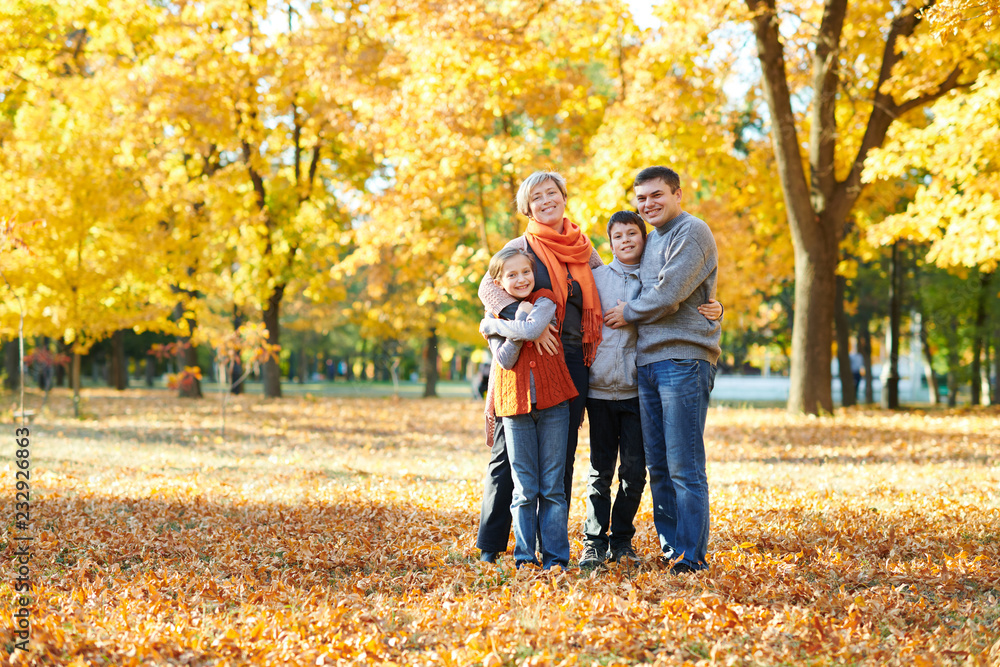 Obraz premium Happy family walks in autumn city park. Children and parents posing, smiling, playing and having fun. Bright yellow trees.
