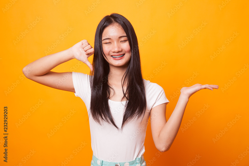 Young Asian woman show palm hand and thumbs down. Young Asian woman show palm hand and thumbs down.