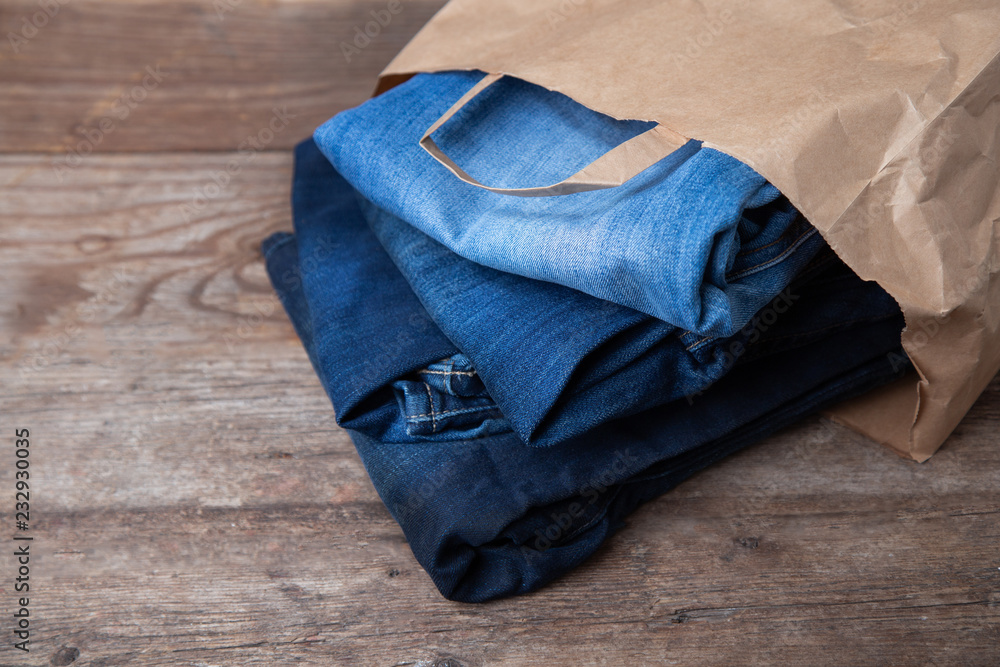 Blue jeans in a paper bag on wooden background. concept purchase.