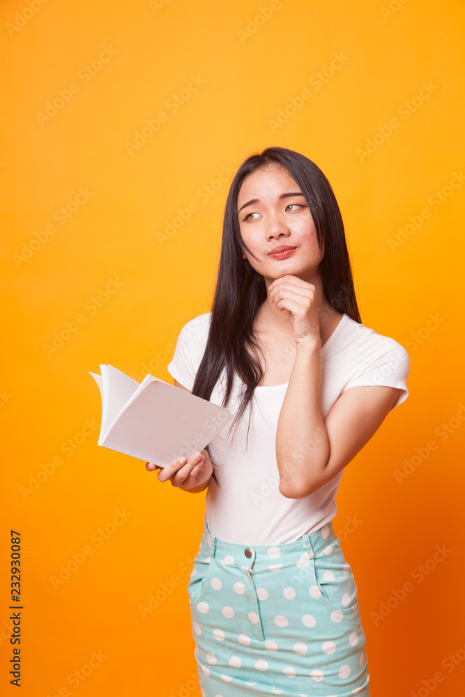Young Asian woman with a book is thinking. Young Asian woman with a book is thinking.