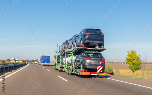 Car carrier trailer with new cars for sale on bunk platform on the highway
