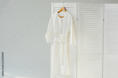 elegant white dress hanging on wooden room divider