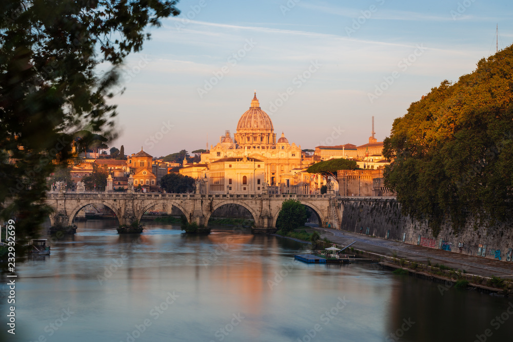 St. Peter's Cathedral in Rome, Italy, and the Tiber River against blue sky at sunrise