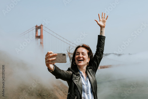 Photography Happy woman taking a selfie with the Golden Gate Bridge, San Francisco