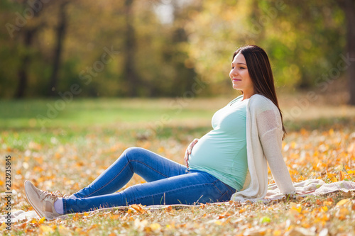 Happy pregnant woman relaxing in park.