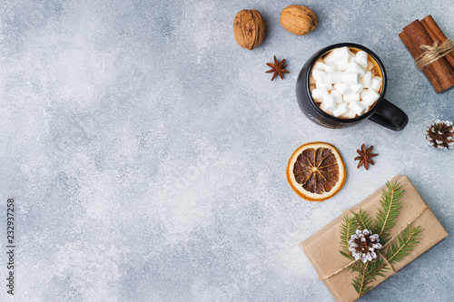 marshmallows in a mug, gift spices and nuts on a gray background with copy space. The concept of Christmas and New Year.