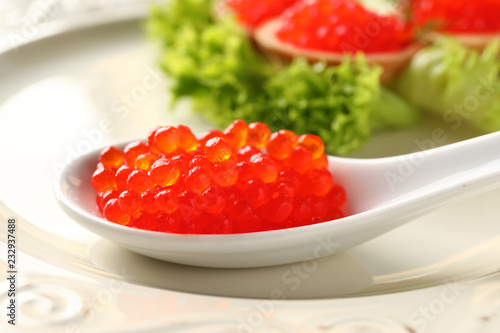 Spoon with tasty red caviar on plate, closeup