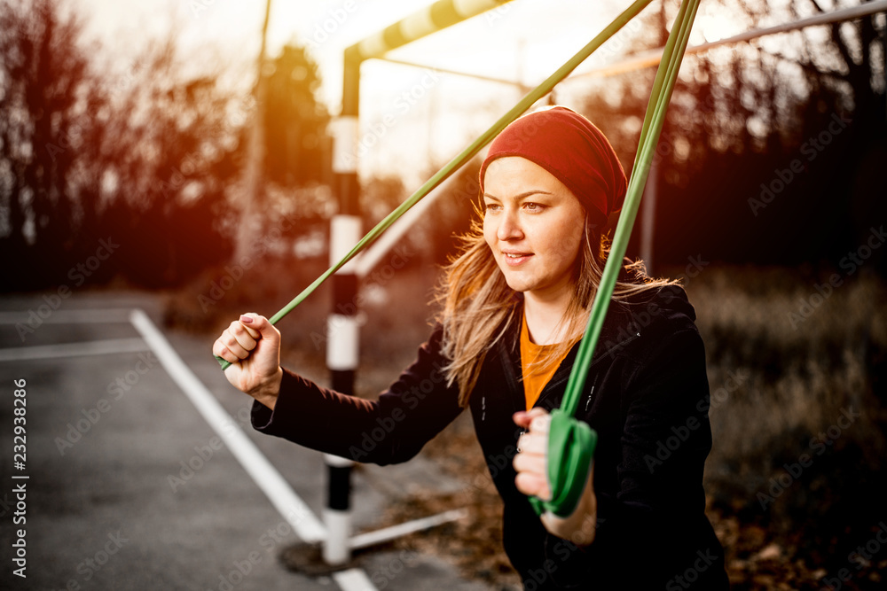 Young woman exercising with resistance band on the playground Young woman exercising with resistance band on the playground
