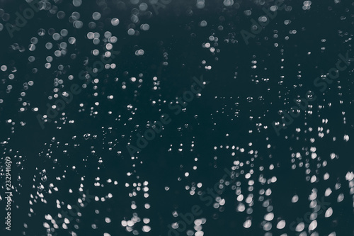 bokeh of lights made by raindrops on a windows illuminated by a torch, abstract background or texture shot