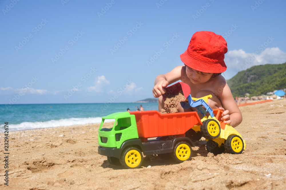 Little boy play in sand on beach. Child playing with a track and excavator in sand Little boy play in sand on beach. Child playing with a track and excavator in sand