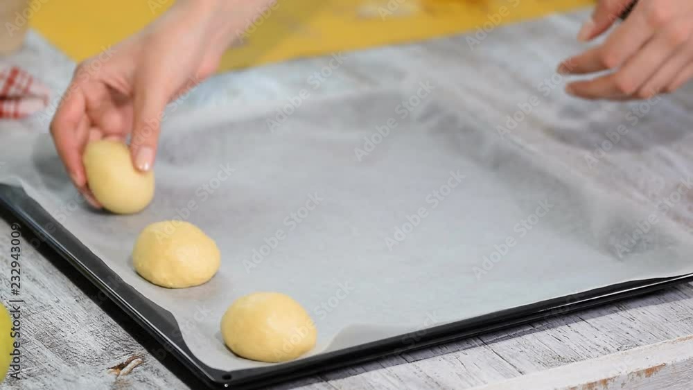 Yeast buns before baking, lie on baking sheet with baking paper. Cooking process. Yeast buns before baking, lie on baking sheet with baking paper. Cooking process.