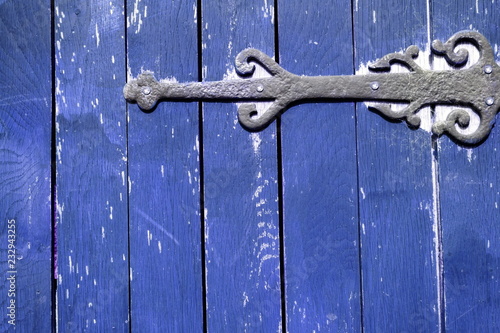 Detail of blue wooden gate with rusty iron hinge
