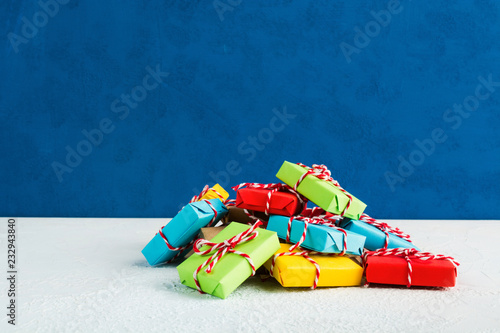 Stack of colorful gifts over white background with blue wall