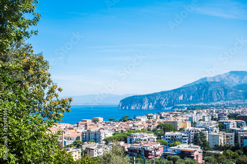 Above view of Sorrento Naples Campania Italy holiday beautiful city place. Mediterranean scenic place with blue sea and high cliffs mountains. Naples and Vesuvio in background © simona