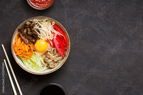 Traditional Asian Bibimbap dish with rice and vegetables on dark background