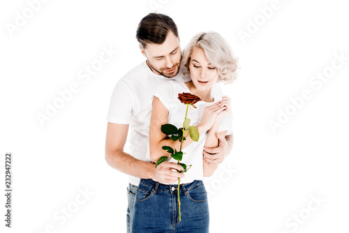 Beautiful couple with flower hugging while man giving to woman red flower isolated on white