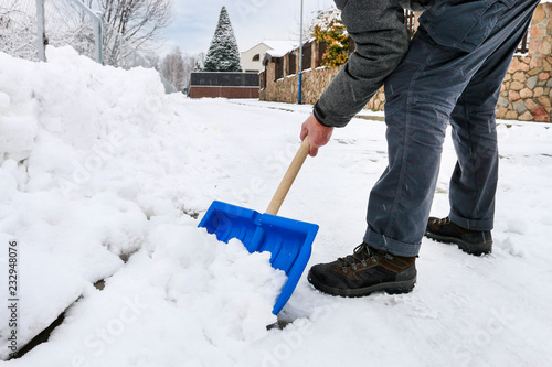 Man removing snow from the sidewalk after snowstorm.