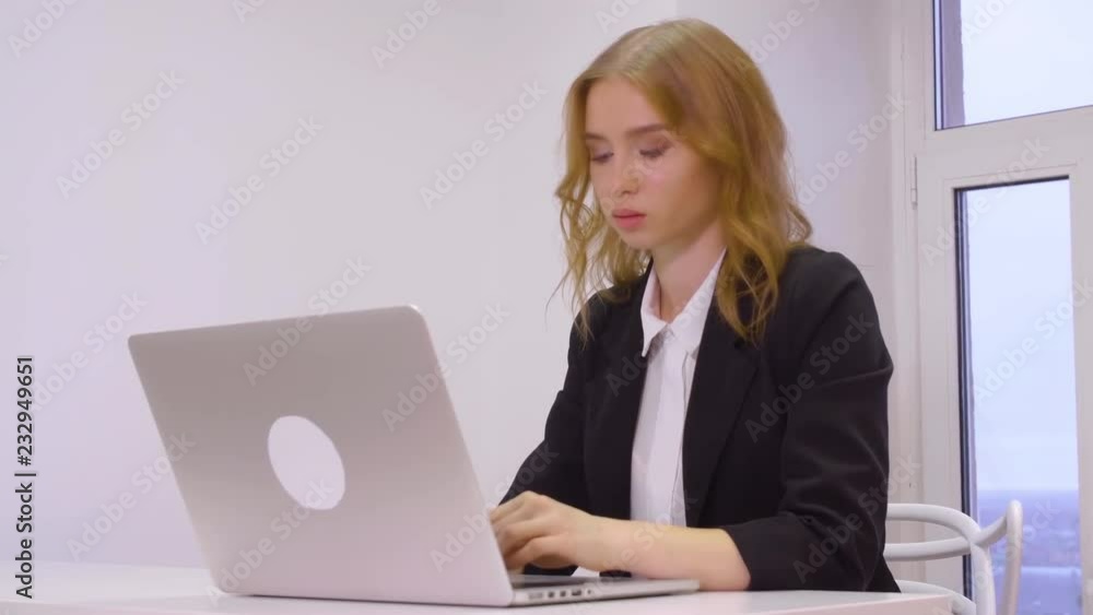 Serious young businesswoman working on laptop at workplace in office Serious young businesswoman working on laptop at workplace in office