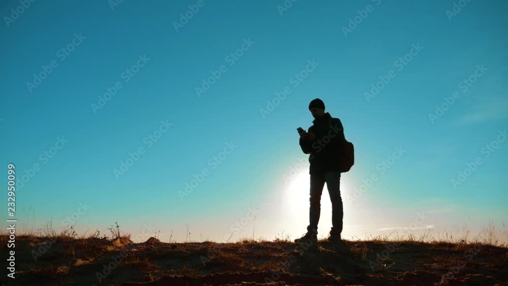 Male man worth it tourist with backpack smartphone navigation sunlight with dog stands on top of a mountain. slow motion video. man silhouette at sunset. hikers adventure and the dog go walking Male man worth it tourist with backpack smartphone navigation sunlight with dog stands on top of a mountain. slow motion video. man silhouette at sunset. hikers adventure and the dog go walking