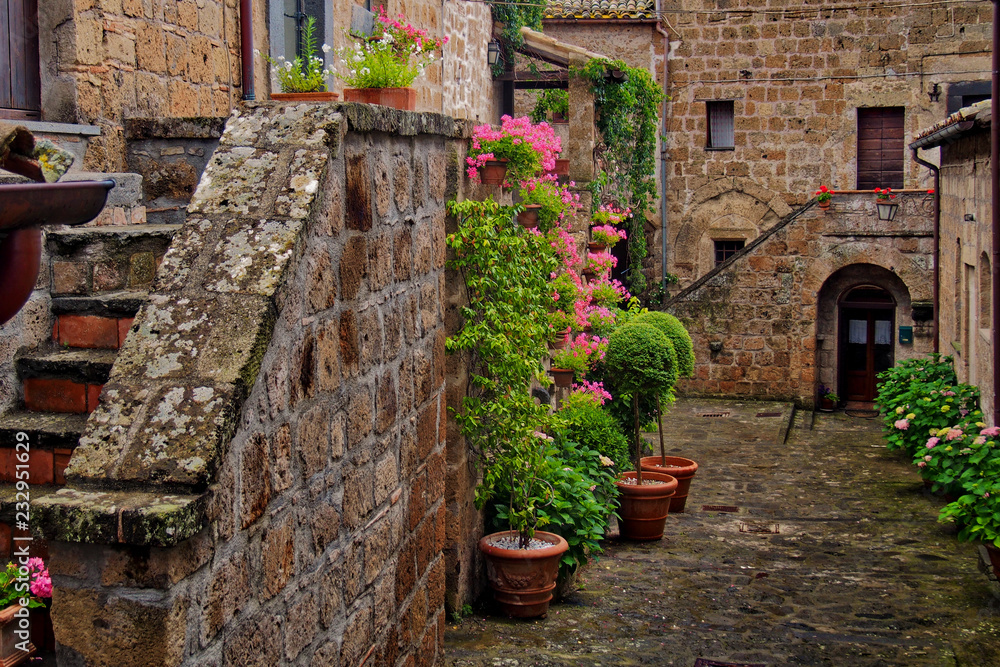 Photo of romantic square in ancient town Civita in Italy with flowers and stairs