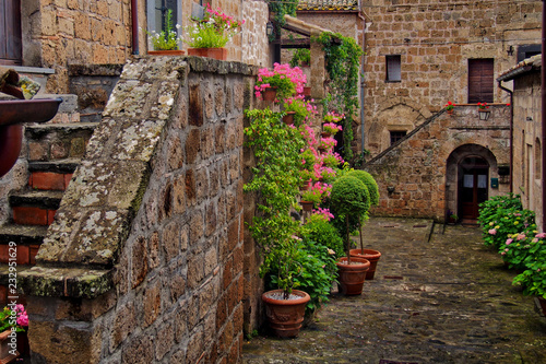 Photo of romantic square in ancient town Civita in Italy with flowers and stairs