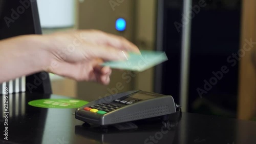 Woman tapping credit card on payment terminal.