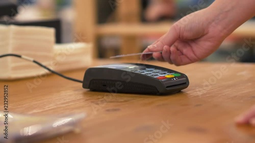 Woman tapping credit card on payment terminal.