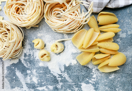 Mixed types and shapes of italian pasta on grey stone, background