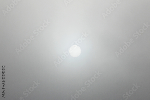 Moon in the sky during the day in heavy fog