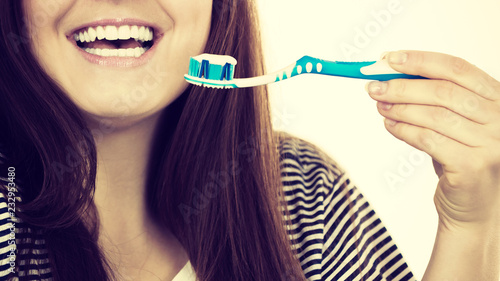Woman holds toothbrush with paste.
