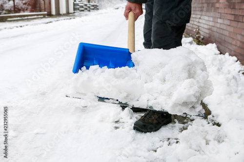 Man removing snow from the sidewalk after snowstorm.