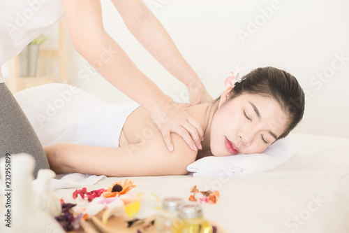 Young asian woman enjoying relaxing back massage in spa. Body care, skin care, wellness, alternative medicine and relaxation Concept.