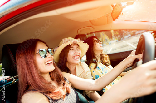 Enjoying woman with her girlfriend in red car summer vacation, holidays, travel, road trip and people concept .