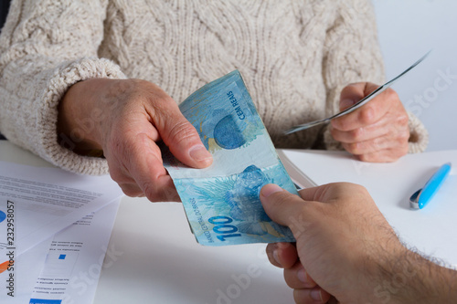 Brazilian currency. Senior person making a loan to a young male at the office. photo