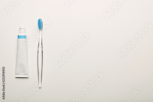top view of toothbrush and toothpaste arranged on white backdrop  dentistry concept