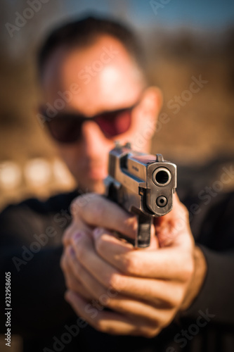 Police agent bodyguard gun pointing pistol to attacker. Front view