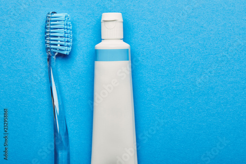 top view of toothbrush and toothpaste arranged on blue backdrop, dentistry concept