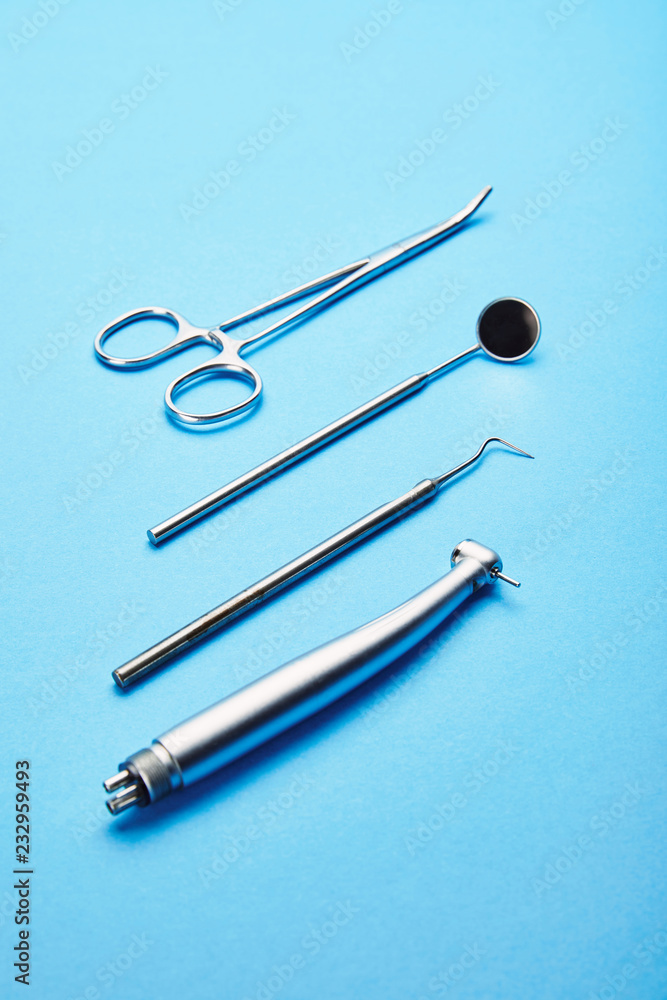 close up view of sterile stainless dental instruments on blue background close up view of sterile stainless dental instruments on blue background